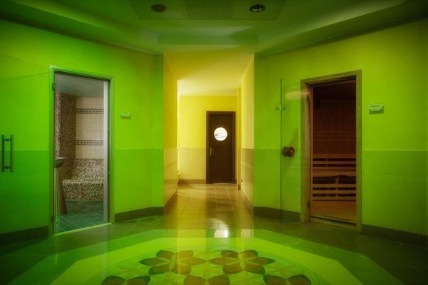 Korytarz z drzwiami prowadzącymi do sauny i łazienki, oświetlony na zielono.