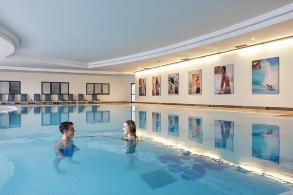 Dwie osoby w krytym basenie obok ściany ze zdjęciami.