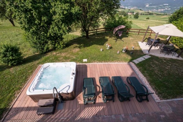 Wanna z hydromasażem i leżaki na tarasie w ogrodzie z widokiem na krajobraz.