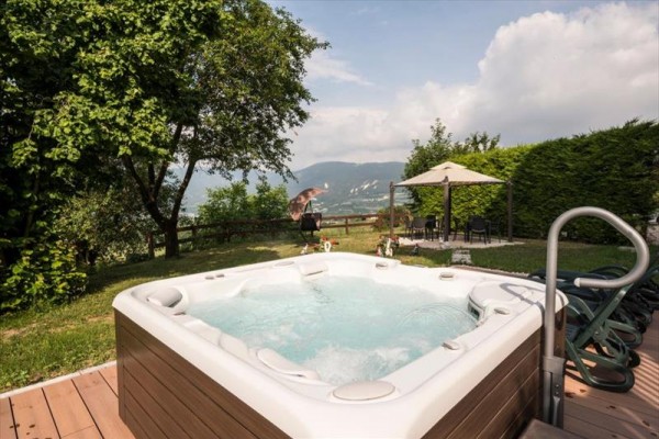 Jacuzzi na tarasie z widokiem na góry i altana w ogrodzie.