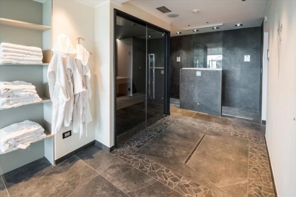 Nowoczesna przestrzeń wellness z półką pełną ręczników i szlafrokami wiszącymi na ścianie.