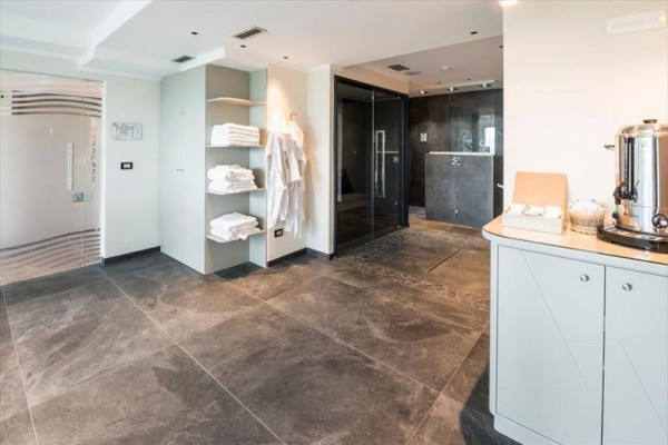 Nowoczesna i przestronna łazienka z otwartą kabiną prysznicową, szafką z ręcznikami i czajnikiem na blacie.