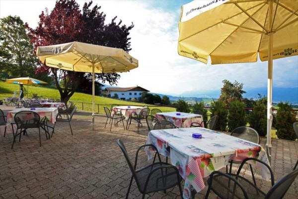 Zewnętrzny taras z kilkoma stołami i krzesłami pod parasolami.