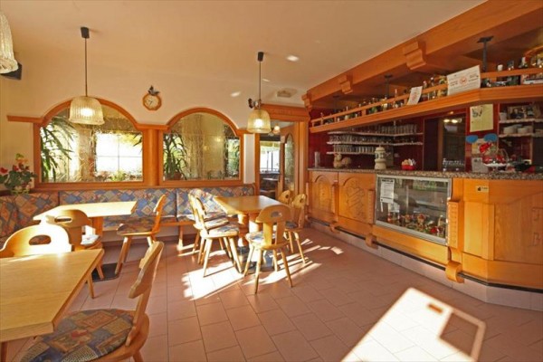 Jasna restauracja z drewnianymi meblami i barem.