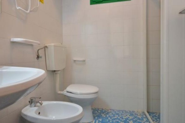 Łazienka z toaletą, bidetem, umywalką i niebieskimi kafelkami na podłodze.