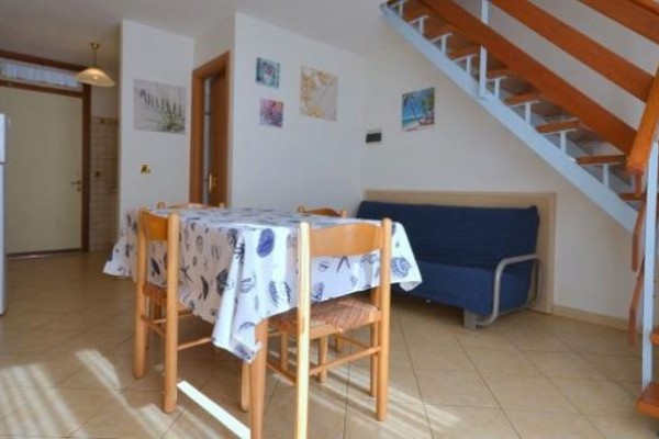 Stół jadalny z czterema krzesłami w środku salonu z kanapą i schodami.