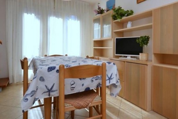 Jasna jadalnia z drewnianymi meblami, stołem i telewizorem.