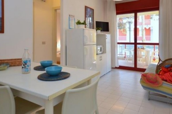 Jasny salon z jadalnym stołem, kanapą i balkonem w tle.