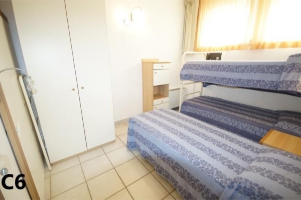 Pokój z piętrowym łóżkiem, pojedynczym łóżkiem, szafą wnękową i komodą.