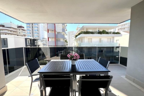 Balkon z czarnym stołem i czterema krzesłami z widokiem na okoliczne budynki.  