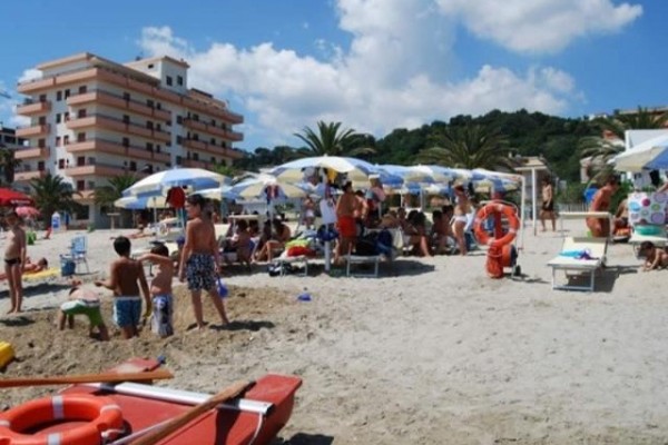 Tętniąca życiem plaża z ludźmi pod parasolami nad morzem.