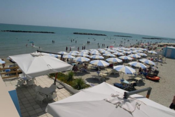 Plaża z rzędem białych i niebieskich parasoli nad morzem.