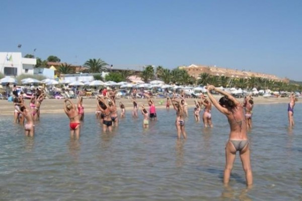 Grupa ludzi ćwiczy w wodzie na plaży.