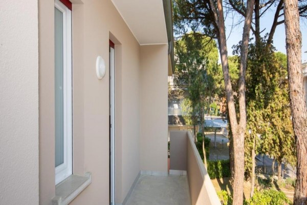 Wąski balkon z widokiem na drzewa i ulicę.