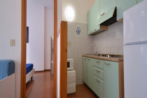 Kuchnia w apartamencie z niebieskimi szafkami i białą lodówką.