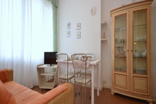 Salon z sofą, stołem jadalnym i witryną.
