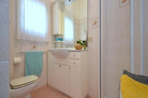 Mała łazienka z umywalką, lustrem i kabiną prysznicową.