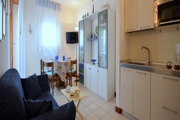 Salon z aneksem kuchennym, sofą, stołem jadalnym i szafą.