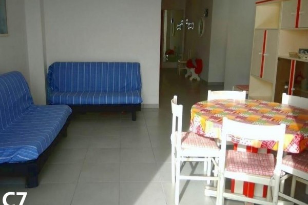 Salonik z niebieskimi kanapami i stołem jadalnianym z kraciastym obrusem.