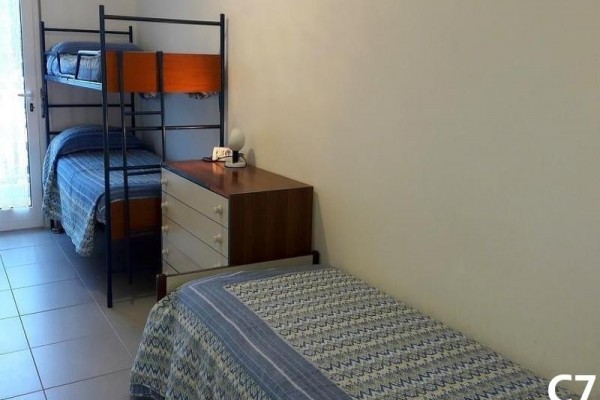 Pokój z pojedynczym łóżkiem, łóżkiem piętrowym i komodą.