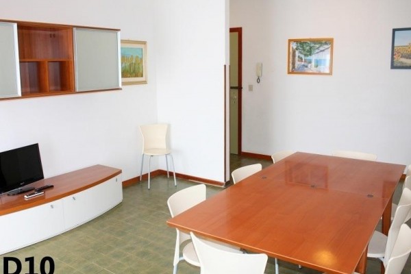 Przestrzeń mieszkalna z dużym drewnianym stołem, krzesłami i telewizorem w rogu.