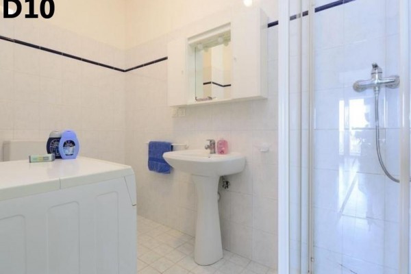 Łazienka z umywalką, prysznicem, lustrem i pralką.