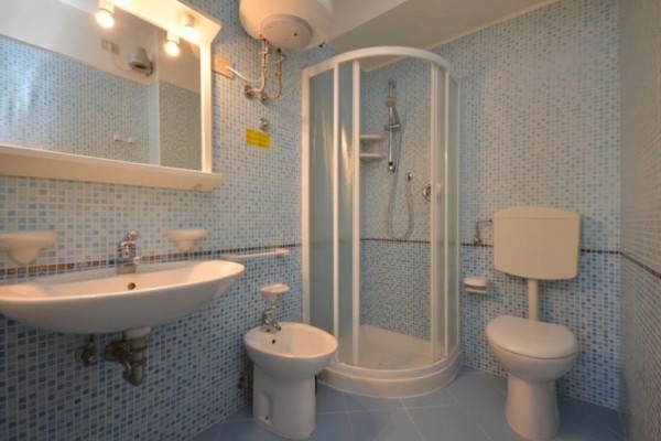 Łazienka z niebieskimi płytkami zawierająca umywalkę, bidet, kabinę prysznicową i toaletę.
